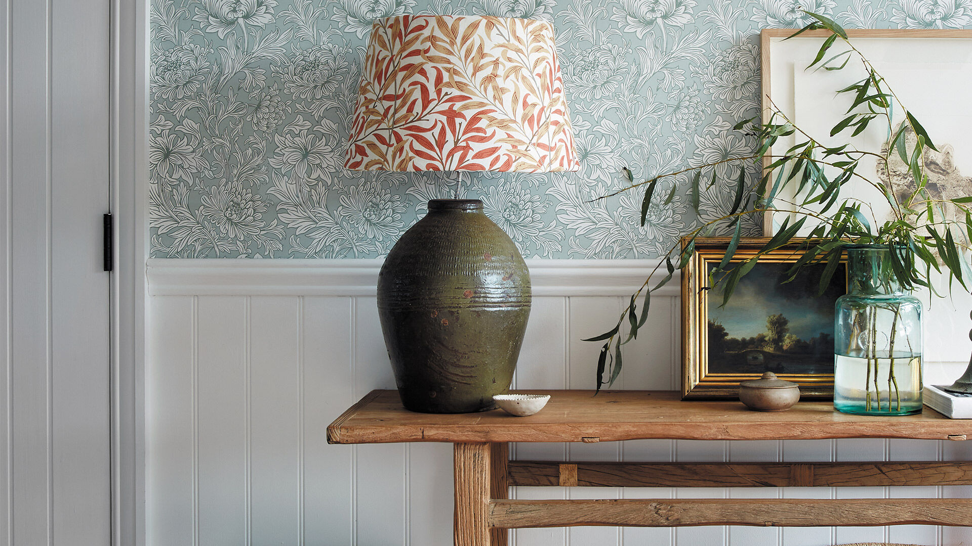 Stuckpaneele und Wandleisten passend zu einer floralen Tapete für einen Flur in Landhausoptik.